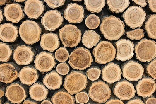 Wooden logs stacked in a pile - header for How to make coffee logs without wax blog
