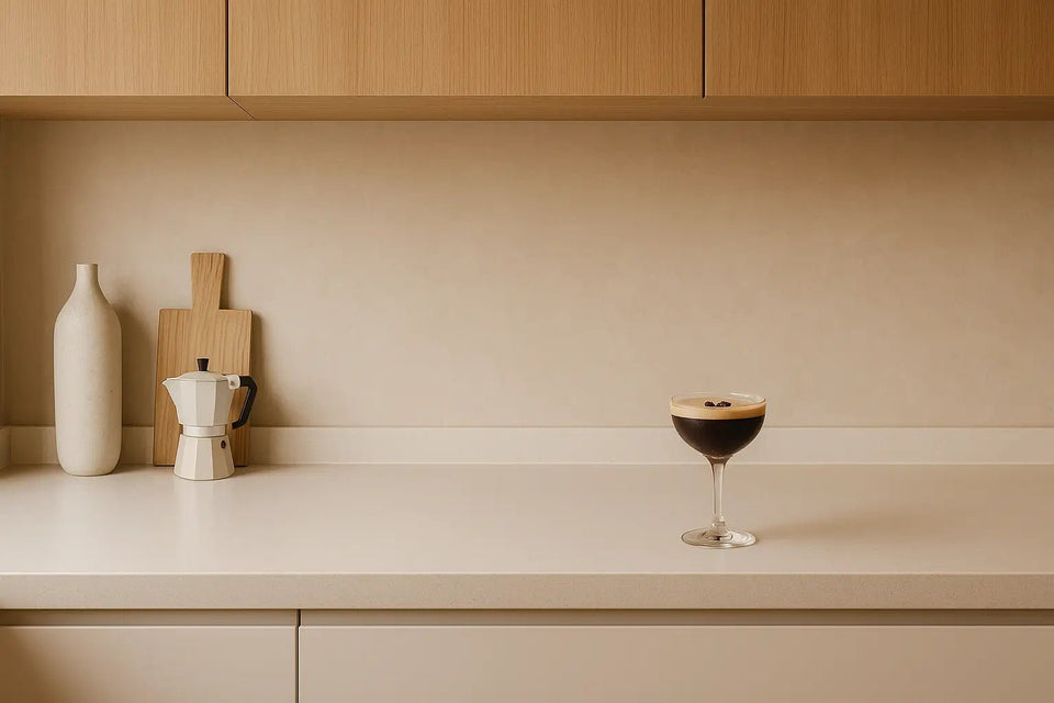 Espresso martini on a wide matte worktop in a Scandinavian kitchen, with pale oak cabinets, soft beige wall, and minimalist props in natural light